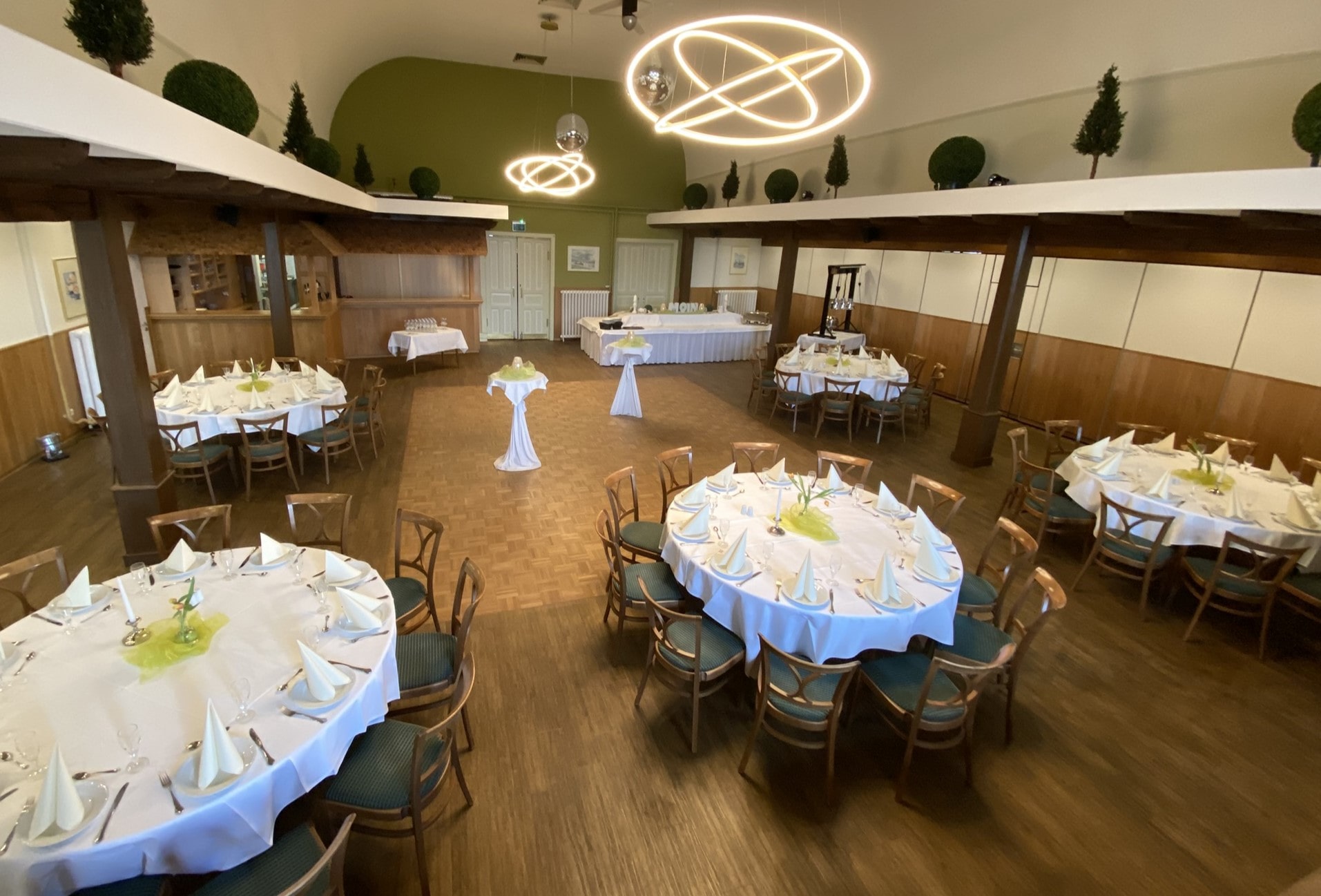 Veranstaltungssaal von Oben mit runden eingedeckten Tischen.